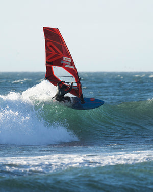Red windsurfing sail with blue Hyper Windsurf Board and black harness