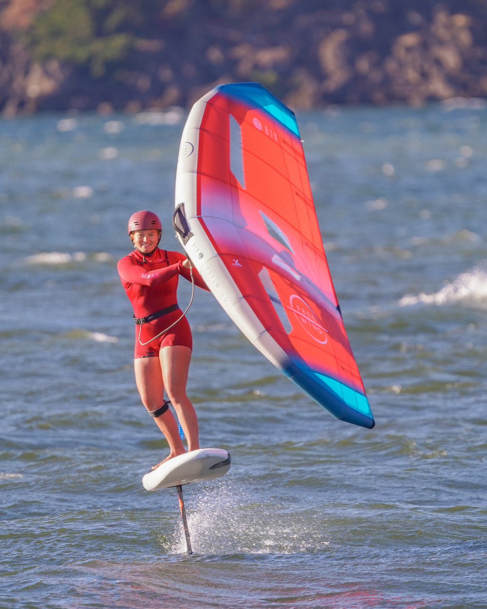Red and blue 2025 Above Foilboard with white fins for windsurfing