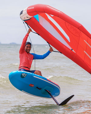 Red and white windsurfing sail on 2025 Above Air Foil inflatable foilboard with blue board and black fins