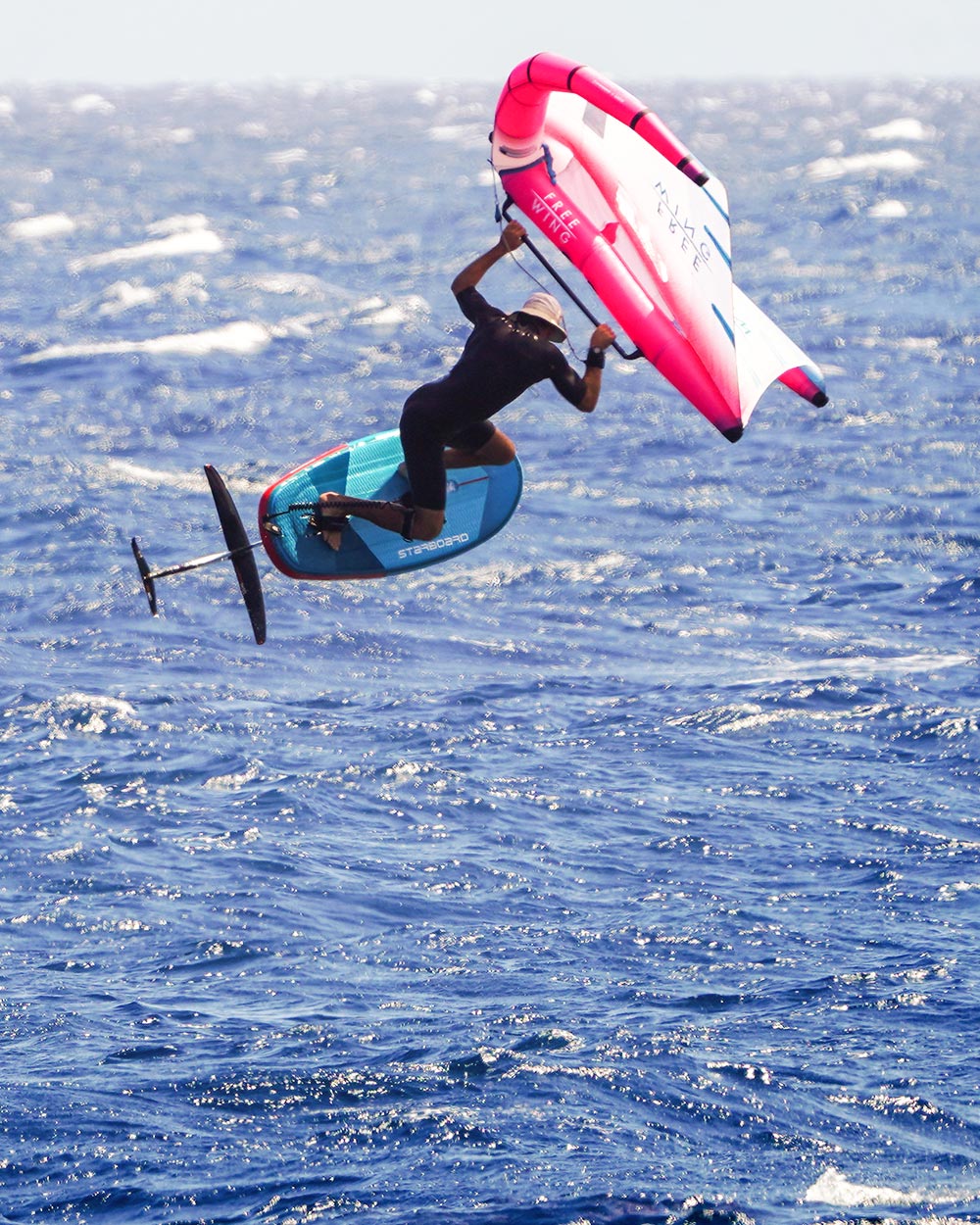 Starboard’s innovative Take Off Air Foil inflatable foilboard with pink and white sail and blue board