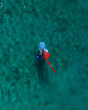 Red and blue neoprene wetsuit with white fins for Millennium Windfoil Board
