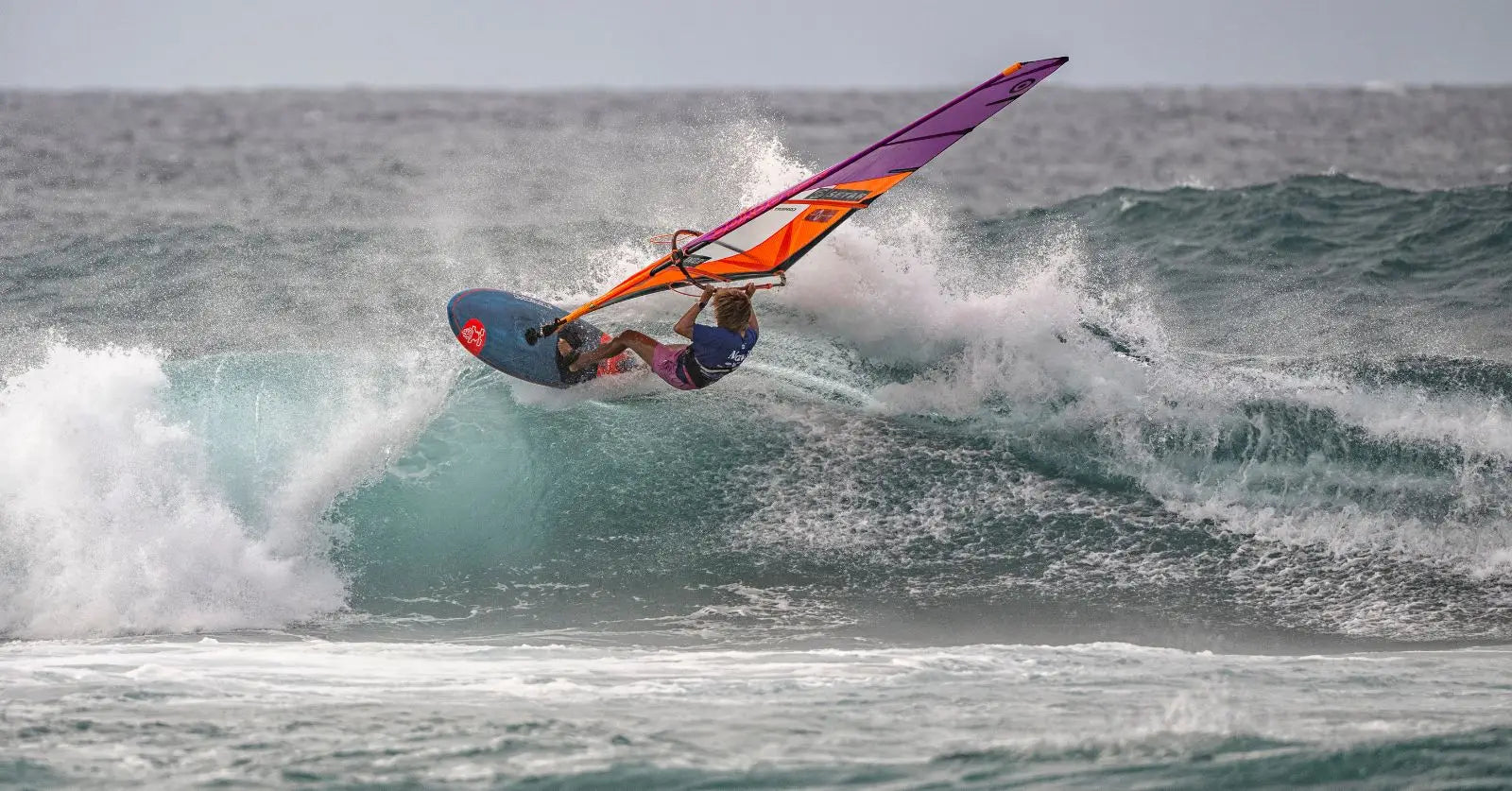 Sarah-Quita with orange purple sail and blue board at 2025 Aloha Classic