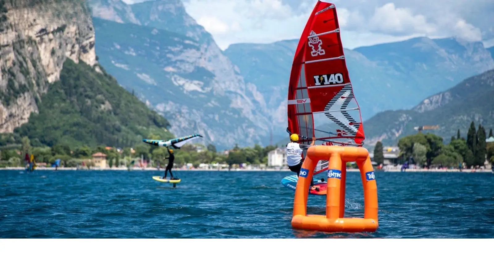 Red and white windsurfing sail with orange buoyancy aids for recreational use
