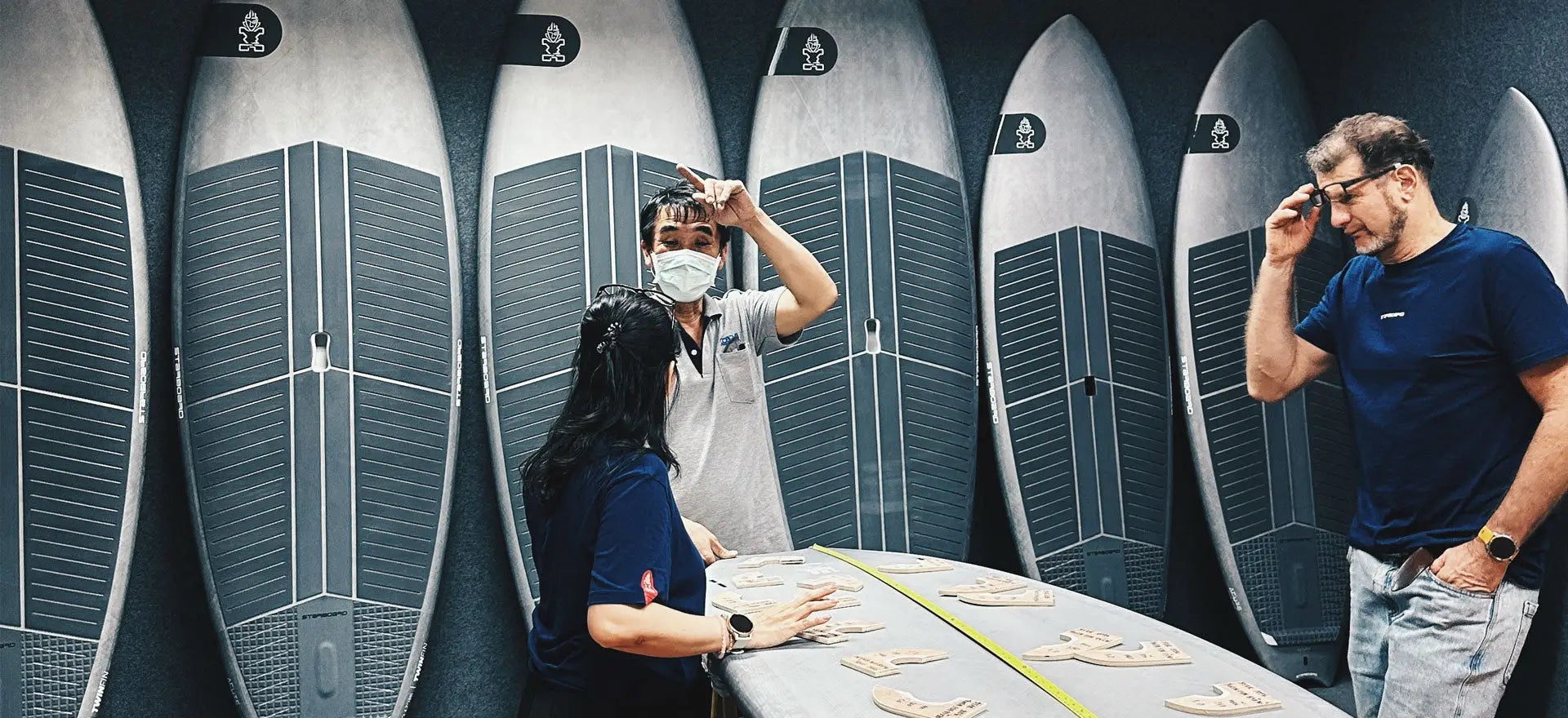 Gray TwinFin surfboard with black textured panels in production