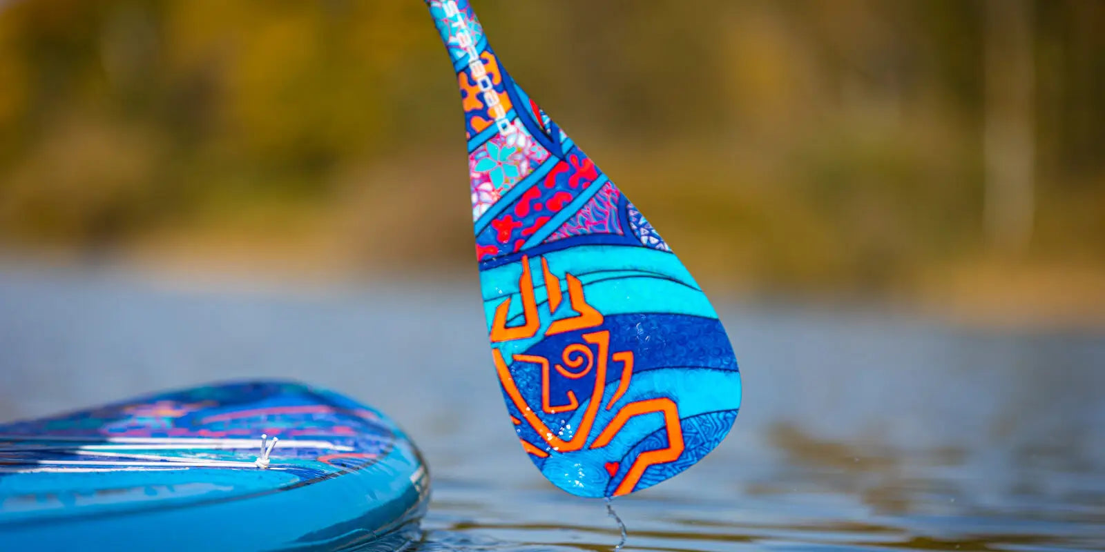 Blue and orange SUP paddle with intricate fiberglass designs