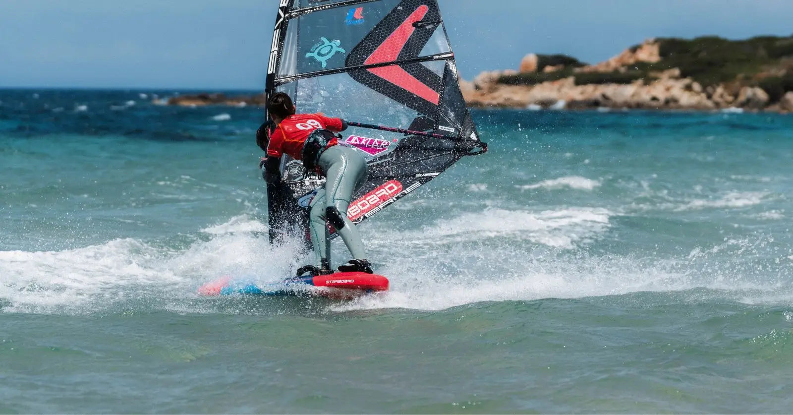 Red and black Starboard windsurfing board with sail at FPT Sardinia