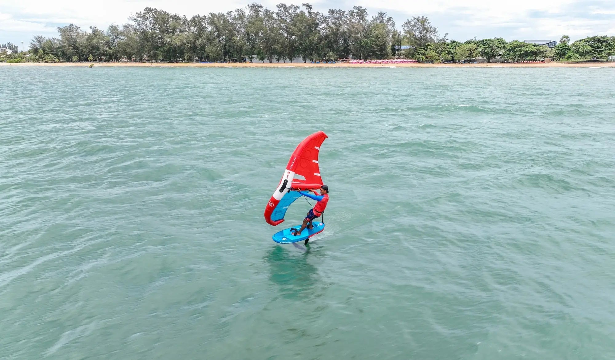 Red and blue hydrofoil board with white fins for wing foiling in Thailand