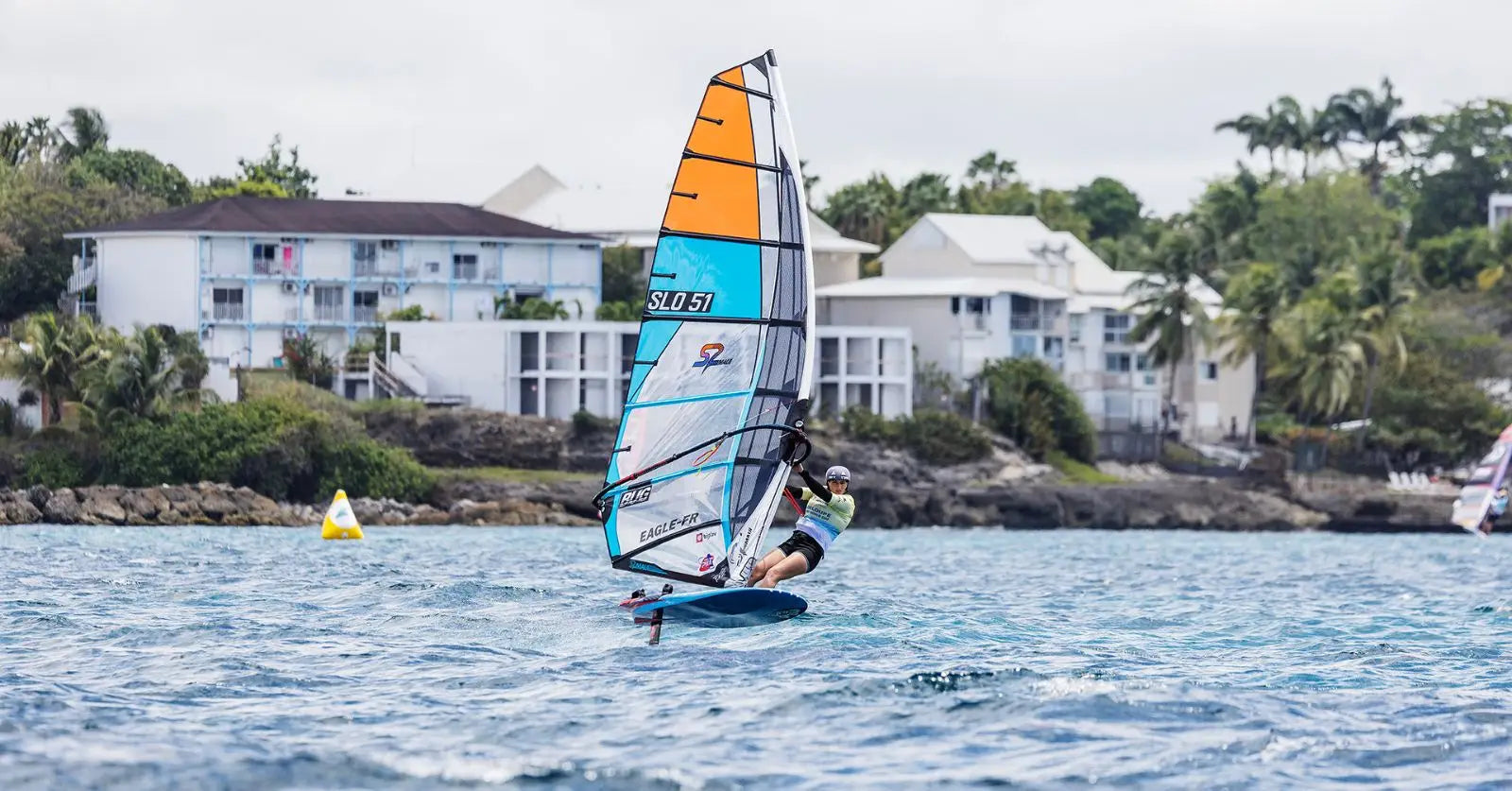 Blue and orange Starboard windsurfing board with white sail for recreational use