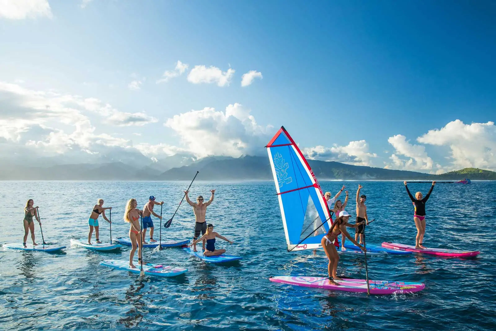 Pink windsurfing board with blue and red recreational sail
