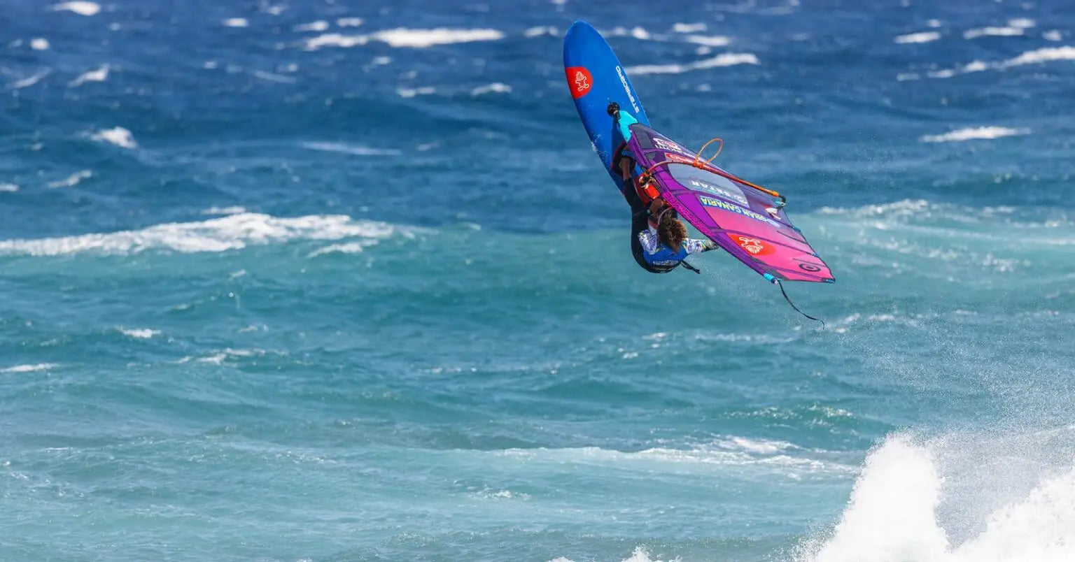 High-performance blue windsurfing board with purple pink sail in Sarah-Quita Pozo article