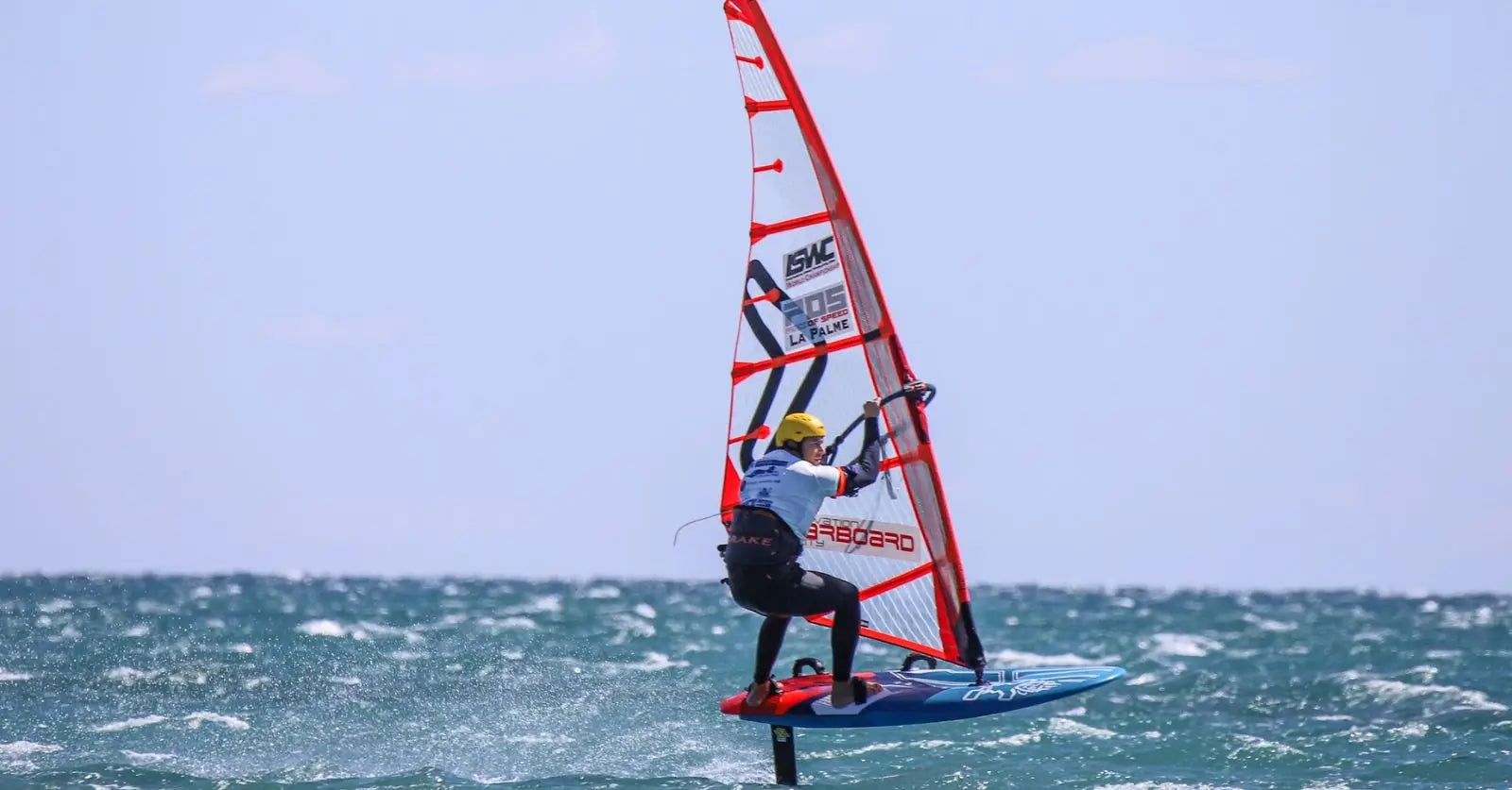 Matteo Iachino on red and white windsurfing sail with blue board