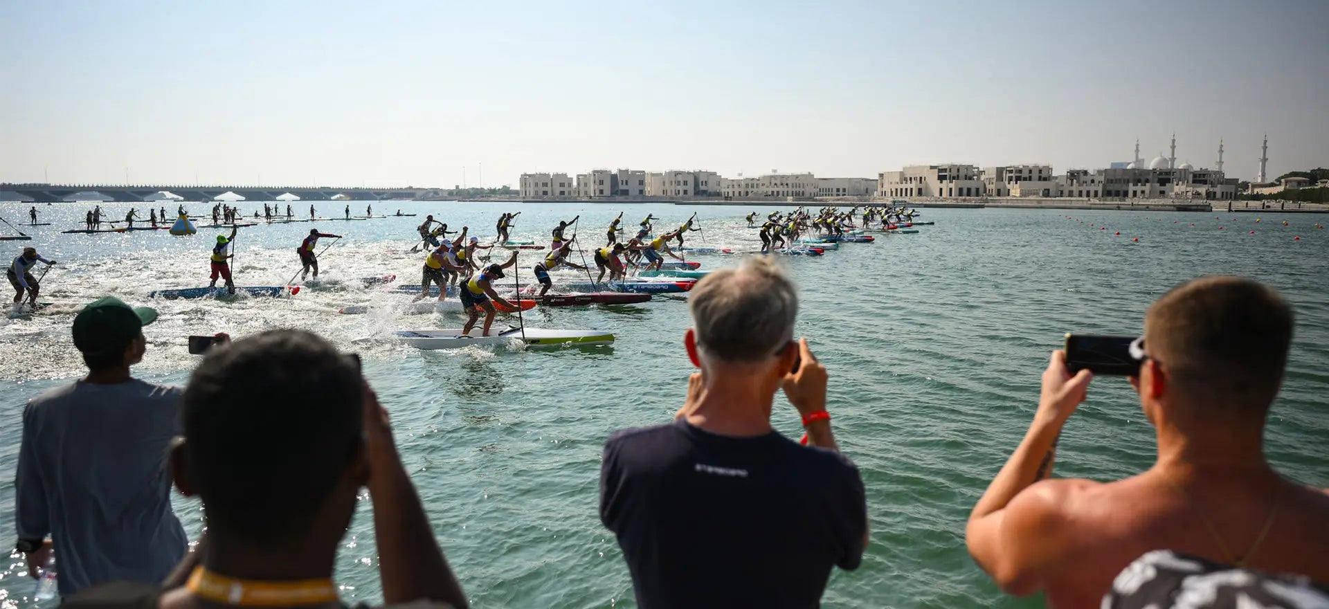 Starboard SUP racers in colorful wetsuits paddle at ICF Worlds
