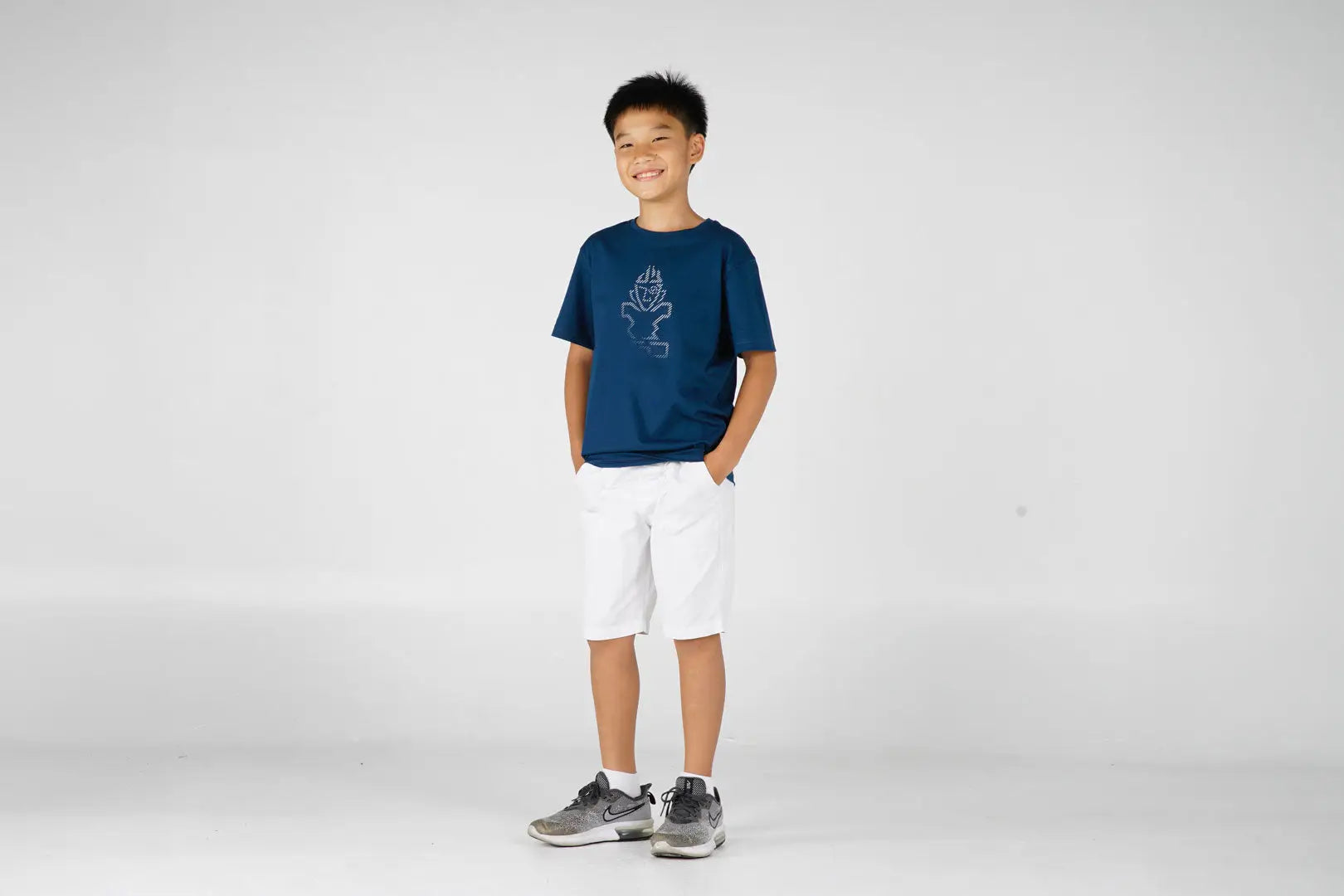 Boys navy blue graphic t-shirt with white shorts and gray sneakers
