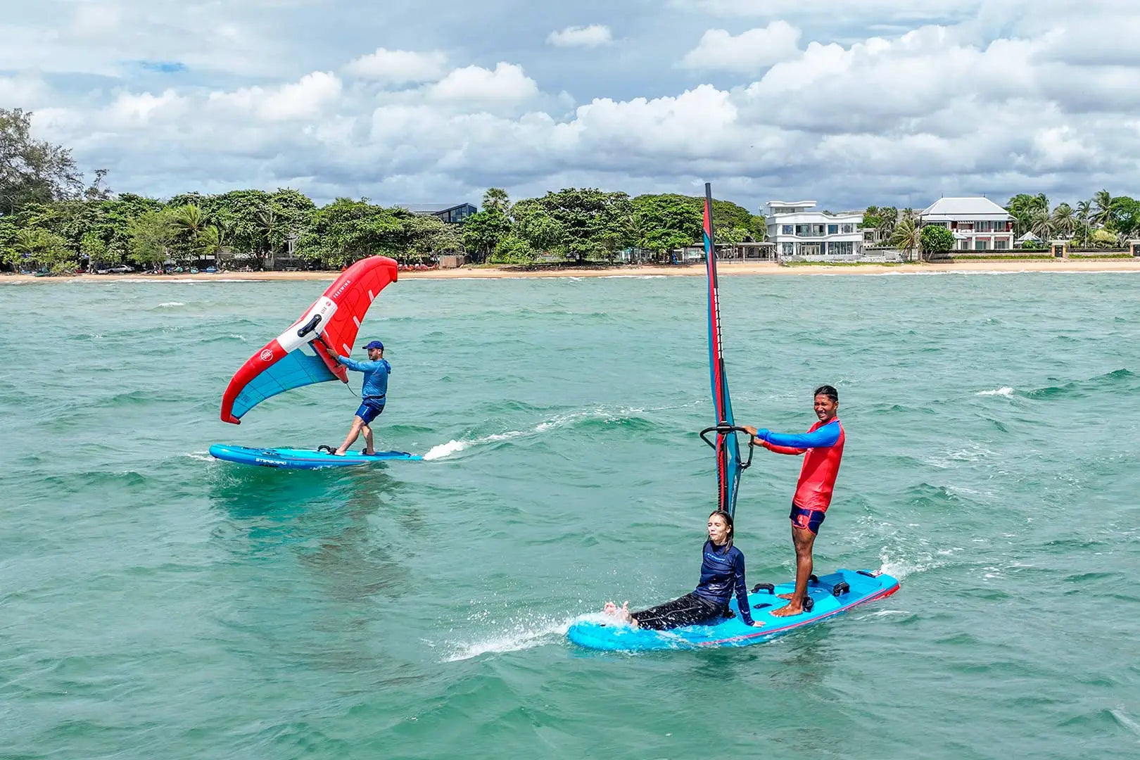 Blue windsurfing board with red sail and black mast in Crossover Inflatable Boards
