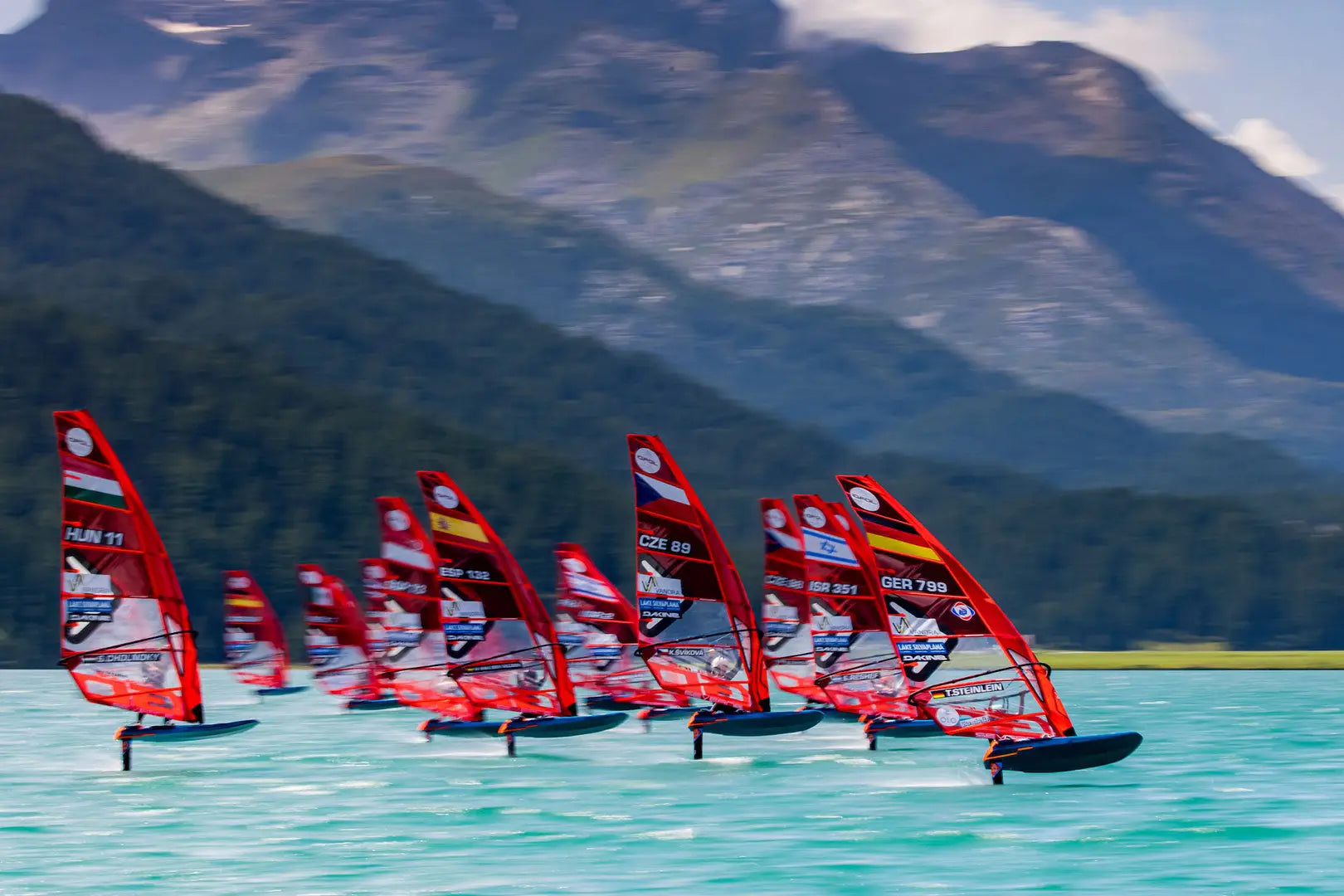 Red iQFOiL windsurfing board with black fins and white logo sails