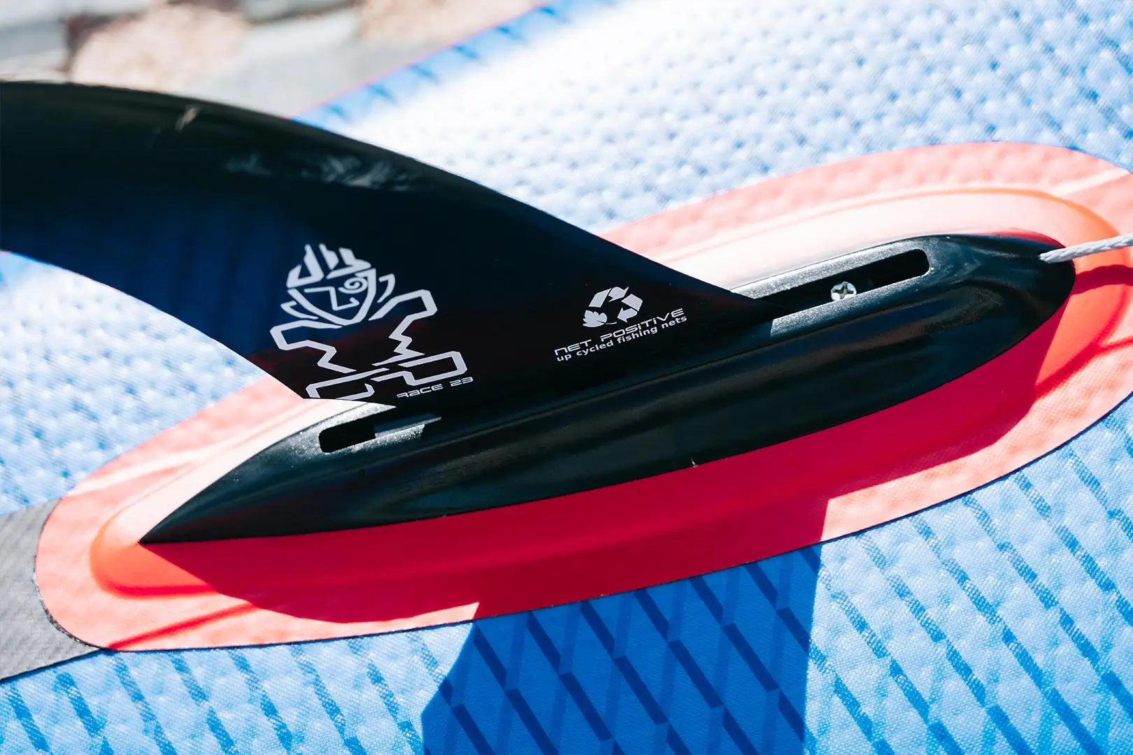 Black surfboard fin with white logo and red accents from Net Positive SUP Fins