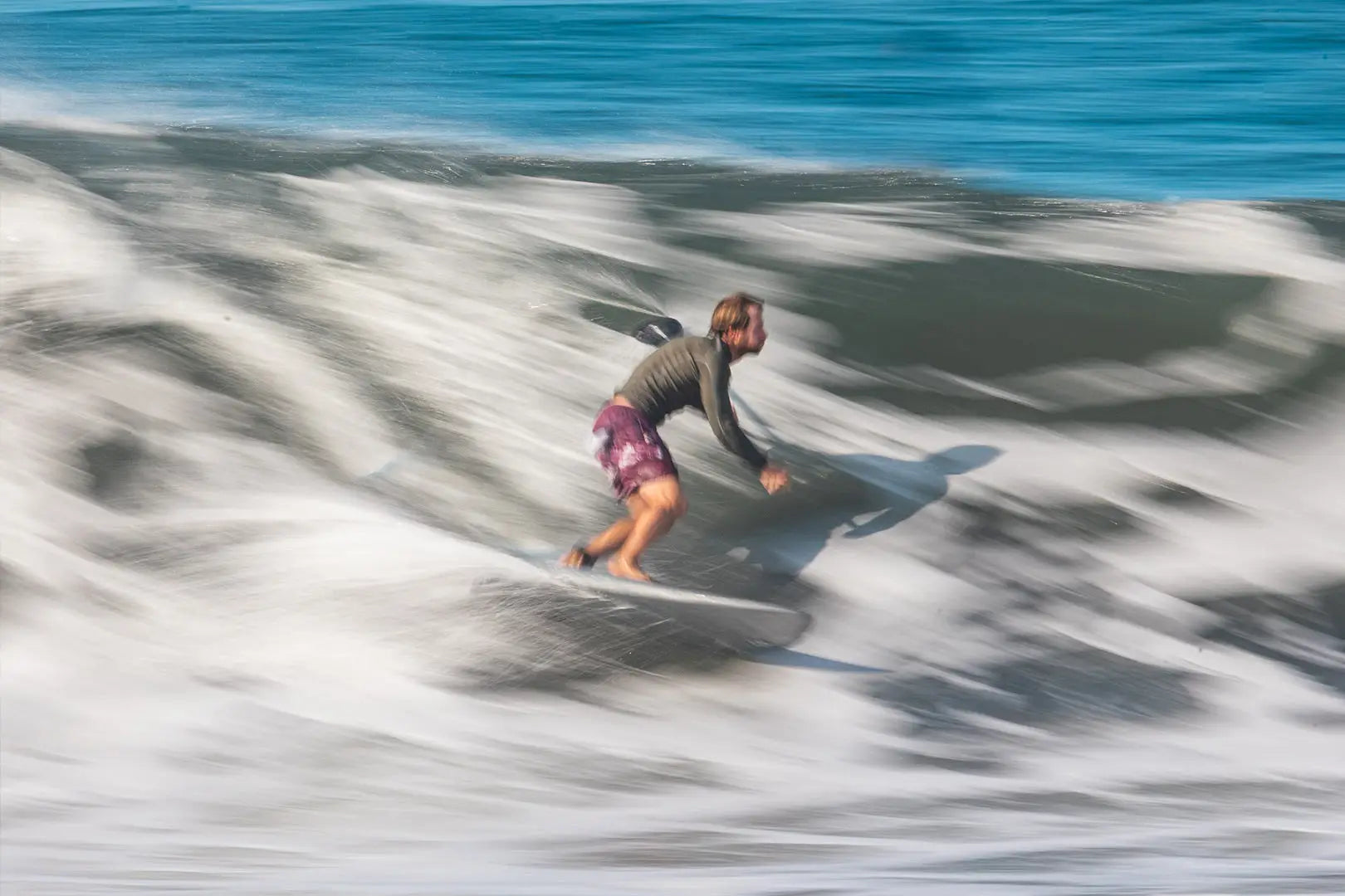 Performance surfboard with white deck and black leash in Spice Paddleboards