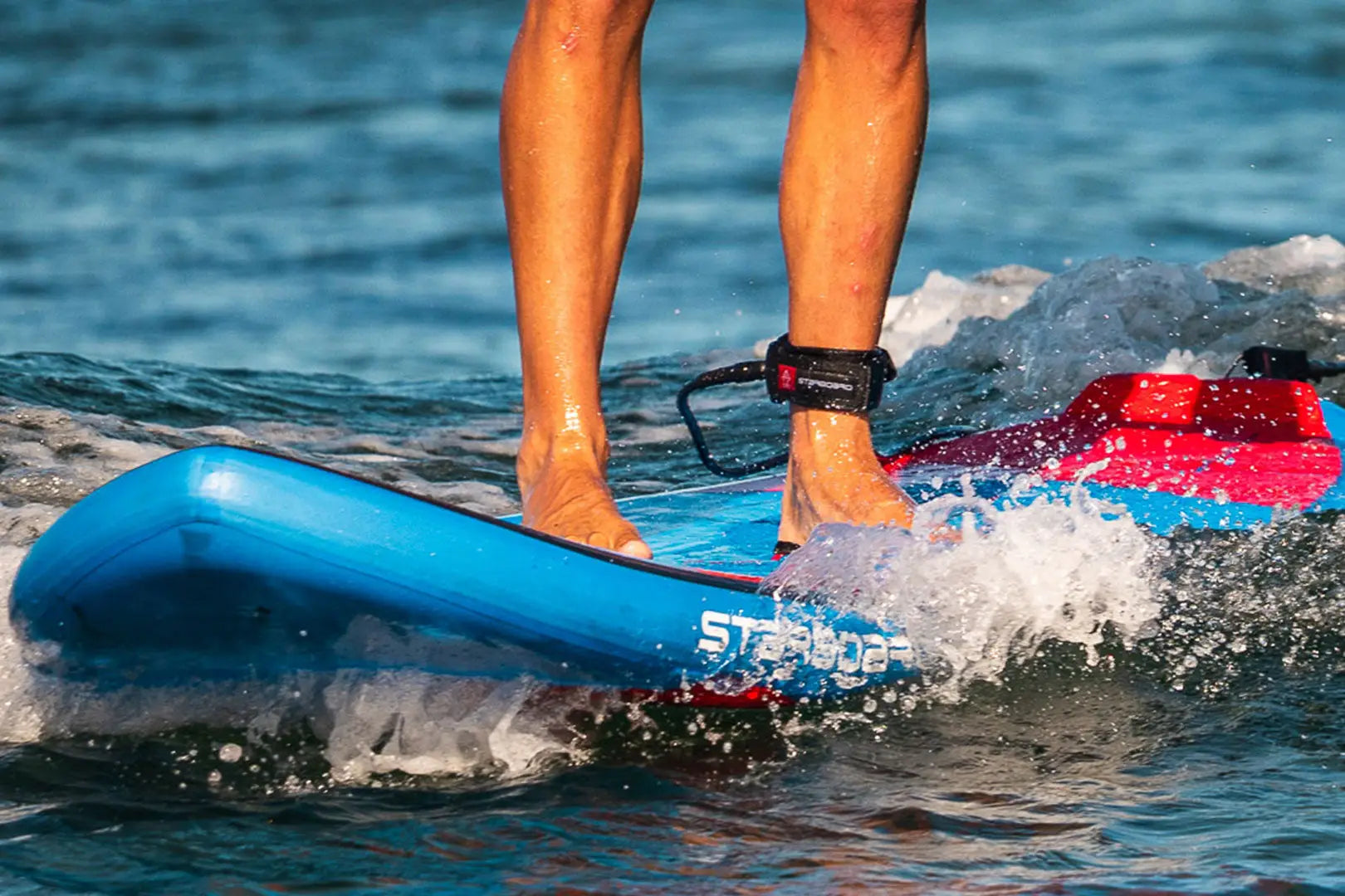 Blue starboard paddle board with red and white accents for SUP leashes