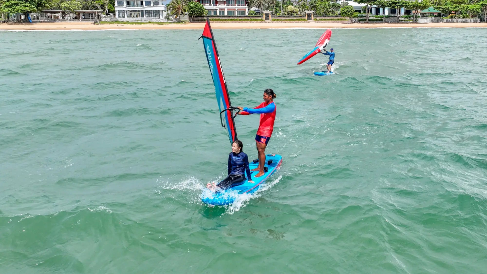 Blue SUPWindsurfing Inflatable windsurfing board with red sail and black fins