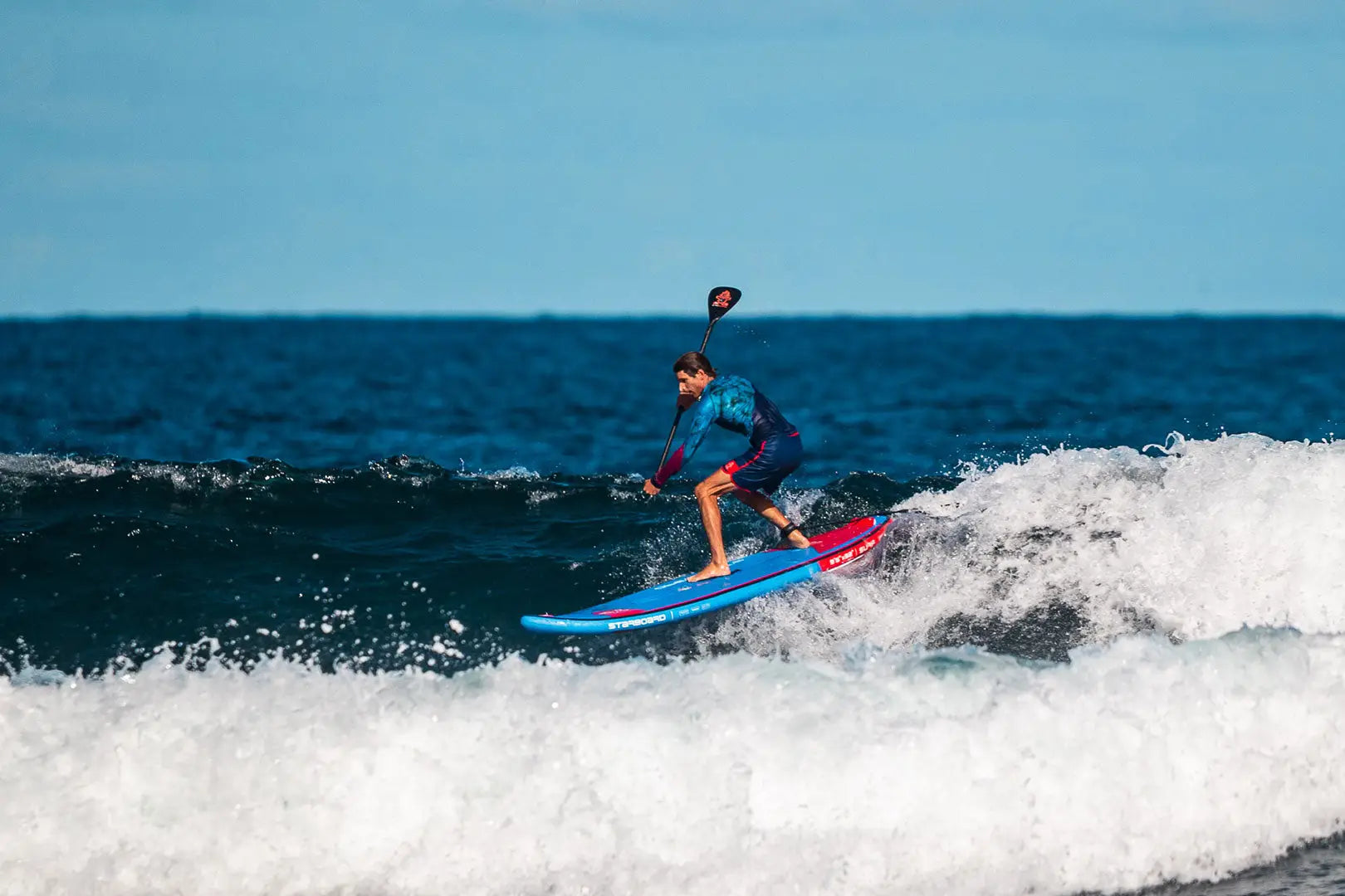 Blue surfboard with red fins, white wave design, polyurethane foam