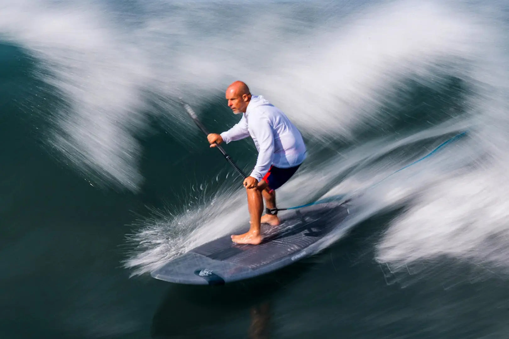 Blue and white paddleboard with red shorts and black leash in Surf Paddleboards