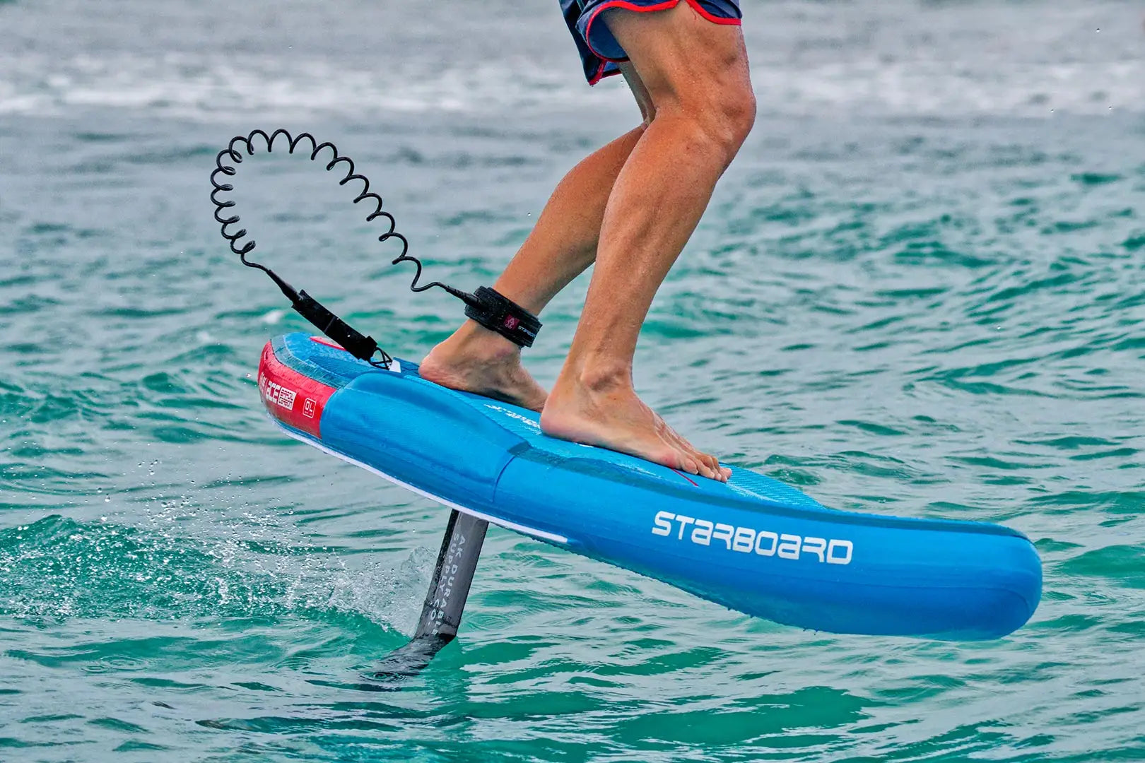 Blue starboard hydrofoil board with red fins and black leash