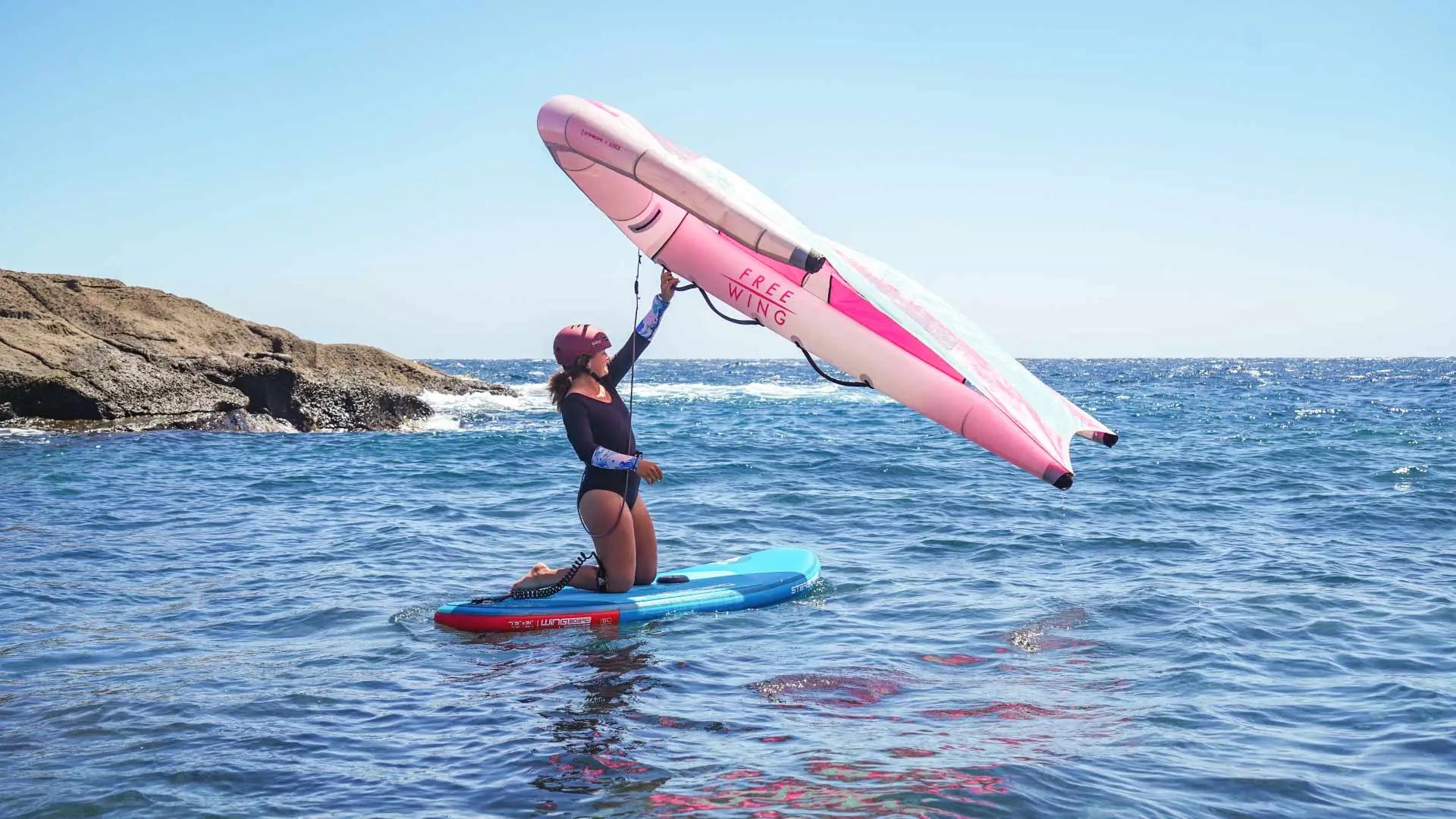 Pink and white paddleboard with black accents from Wingsurf Boards
