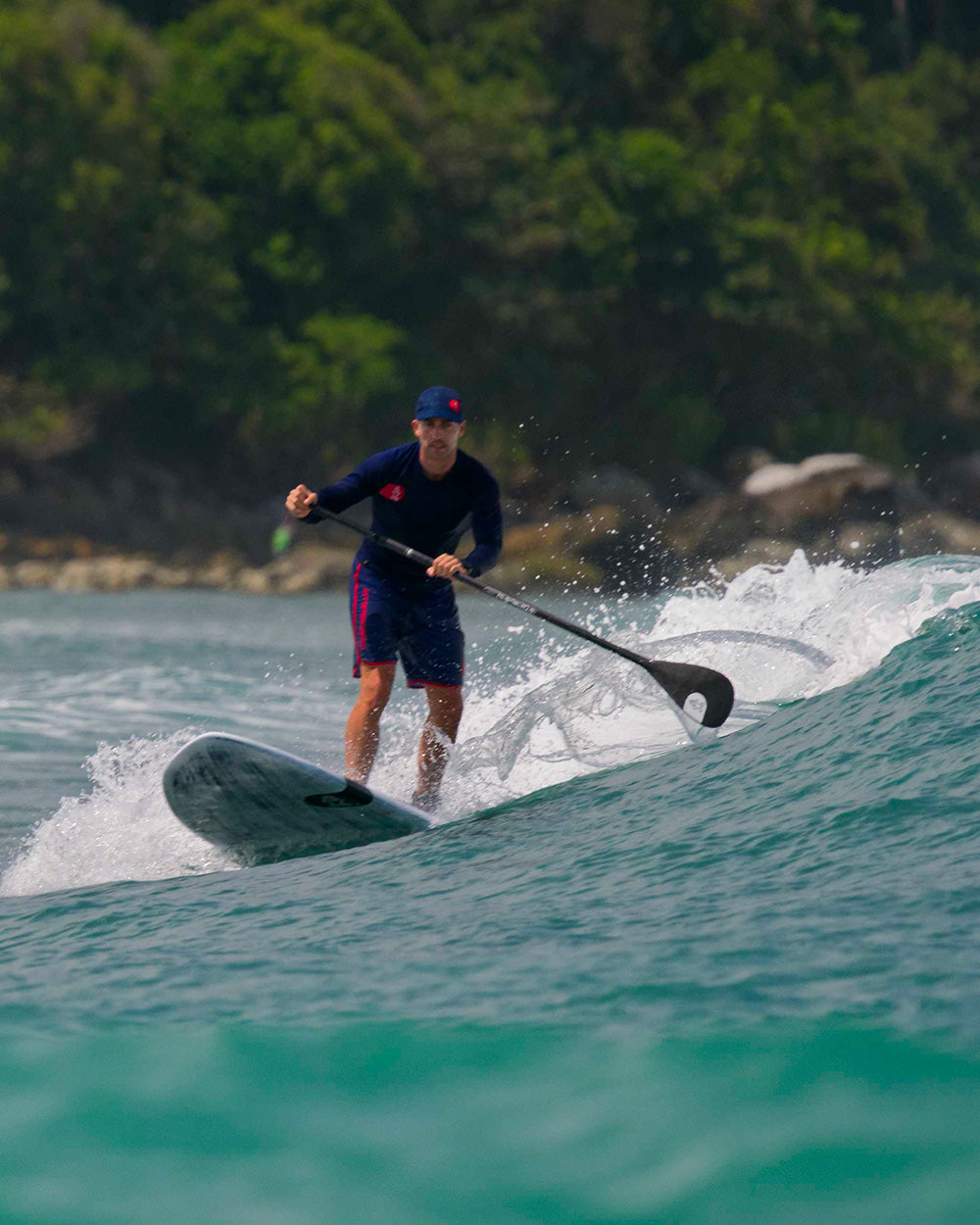 Enduro Carbon Paddle: black and white stand-up paddleboard with blue leash, red fins, foam grip
