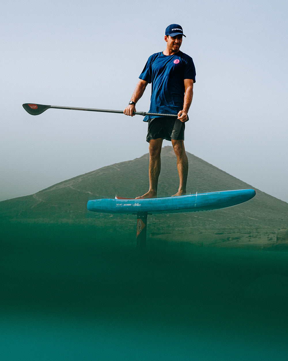 Blue prepreg carbon foil blade paddleboard with black fins, white logo