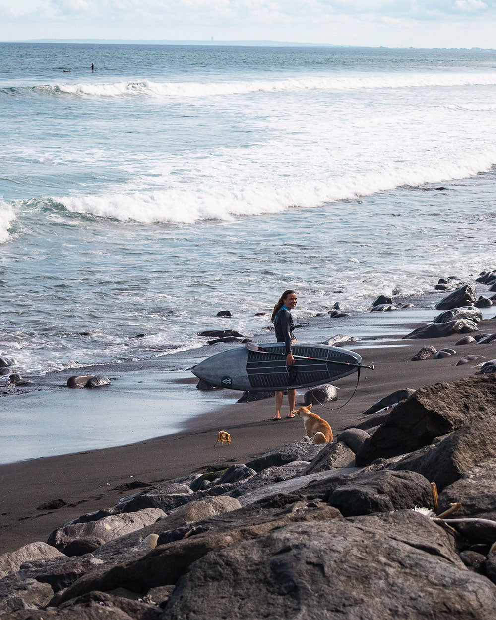 Black fiberglass surfboard with white fins and leash, Spice Paddleboard