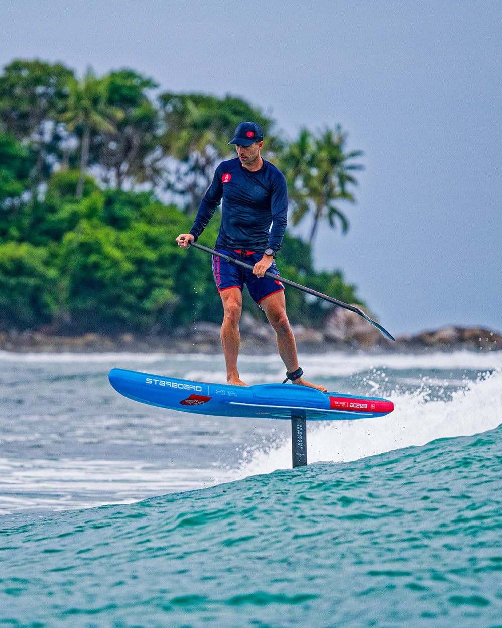 Ace Air Foil Inflatable Foilboard with blue hydrofoil, red fins, black paddle